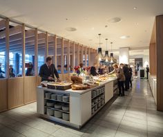 people are standing in line to get food from the buffet counter at an airport restaurant