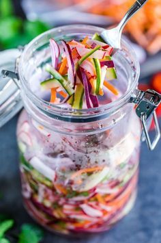 a glass jar filled with sliced vegetables on top of a table