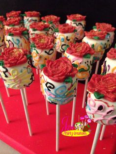 there are many decorated cupcakes on the sticks with flowers and numbers painted on them