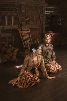 two people are sitting on the floor in traditional clothing