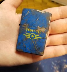 a person holding a blue and yellow lighter in their hand with the words vault tec on it