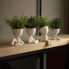 three white ceramic planters sitting on top of a wooden table next to each other