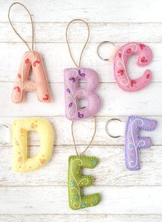 the letters are made out of felt and hang from strings on a white wooden surface