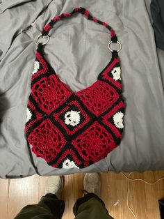 a crocheted purse sitting on top of a bed next to a pair of shoes