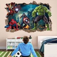 a boy sitting on the floor in front of a wall mural with avengers and spider - man