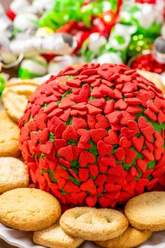 a large red ball covered in hearts surrounded by crackers and candy canes on a white plate