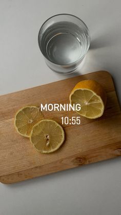 a wooden cutting board topped with sliced lemons next to a measuring cup filled with water