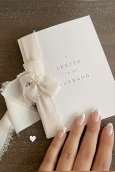 a woman's hand holding a white card with a bow on it and the words, a letter to my husband