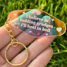 a hand holding a keychain that says i believe in holding grudges i'll heal in hell