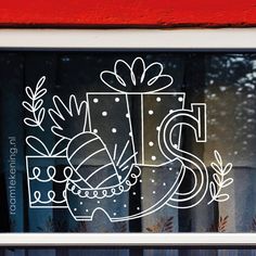 a window with the letter s drawn on it in front of a christmas present box