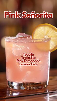 a pink lemonade drink sitting on top of a table next to a slice of lemon