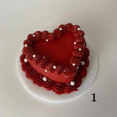 a red heart shaped cake sitting on top of a white plate