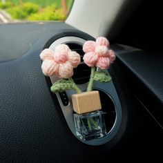 two crocheted flowers are attached to the center console of a car with a wooden block