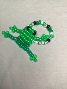 a green and white beaded bracelet with an alligator on it