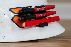 three red crayons sitting on top of a white hard hat