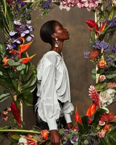 a woman standing in front of flowers and greenery