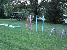 an outdoor play area in the middle of a grassy field with plastic rings and swings