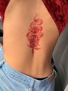 a woman's lower back tattoo with roses on her left side and snake in the middle