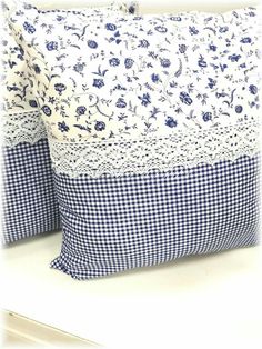 two blue and white pillows sitting next to each other on top of a tablecloth