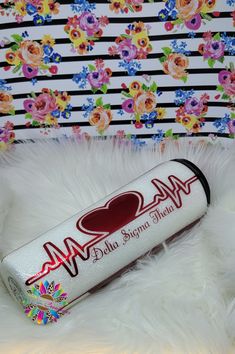 a tube of lipstick sitting on top of a white fur covered floor next to a flowered wall