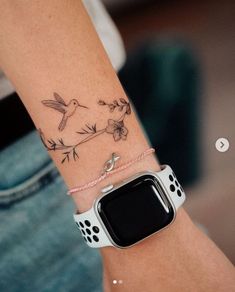 a woman's arm with a bird and flower tattoo on it, she is wearing a white apple watch band