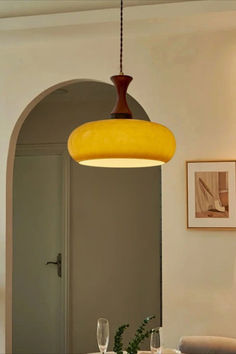 a dining room table and chairs with a yellow light hanging from the ceiling over it