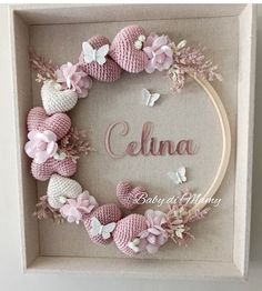 a pink crocheted wreath with flowers and butterflies on it in a white frame