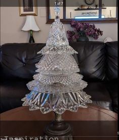 a glass christmas tree sitting on top of a table next to a black leather couch