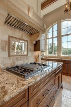 a large kitchen with marble counter tops and wooden cabinetry in front of two windows