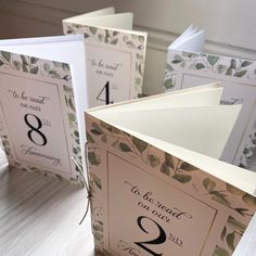 wedding table numbers with leaves and vines are displayed on folded cards that read, to be heard our guests