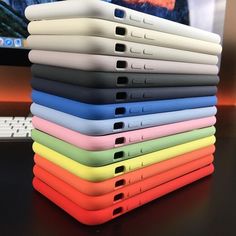 a stack of different colored cases sitting next to a laptop