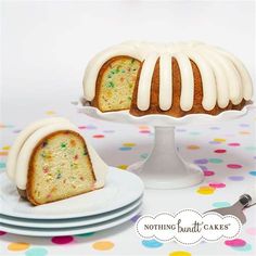 a bundt cake with white frosting and sprinkles on it sitting next to plates