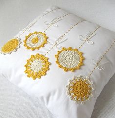 a white pillow with yellow crocheted flowers on it