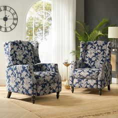 a living room with two blue chairs and a clock on the wall behind them in front of a window