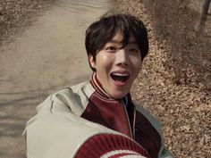 a young man is making a funny face while walking down a dirt path in the woods