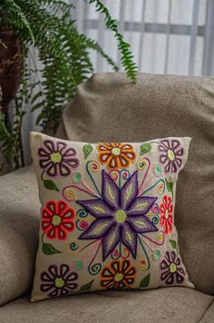 a decorative pillow on a couch next to a potted plant