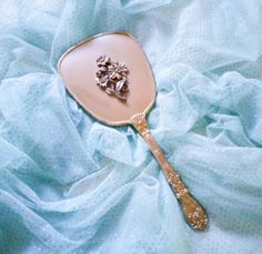 a gold spoon with a flower on it sitting on a blue cloth covered tablecloth