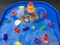 there is a toy boat in the water with toys around it and on top of rocks