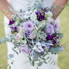 a bride holding a purple and white bouquet