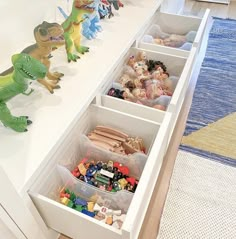 toy dinosaurs and other toys are in bins on the counter top next to drawers