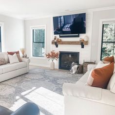 a living room filled with furniture and a flat screen tv mounted on the wall above a fire place