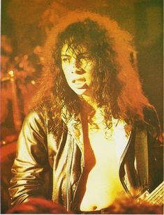 a man with long hair wearing a tie and leather jacket