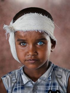 a young boy with blue eyes wearing a white headband and looking at the camera