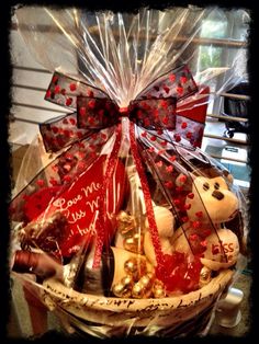 a basket filled with lots of chocolates and teddy bears in red bow ties on top of a table