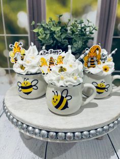 three mugs filled with whipped cream and honeybees on top of a table