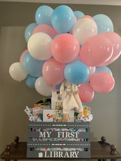 a bunch of balloons that are on top of a book shelf in front of a table