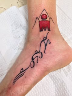 a person with a tattoo on their foot that reads m and has a mountain in the background