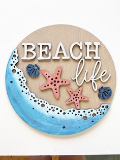 a wooden sign that says beach life with starfish and seashells