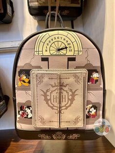 the back side of a backpack with mickey mouse stickers on it, hanging from a hook