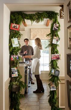 a man and woman standing next to each other in front of a doorway covered with greenery